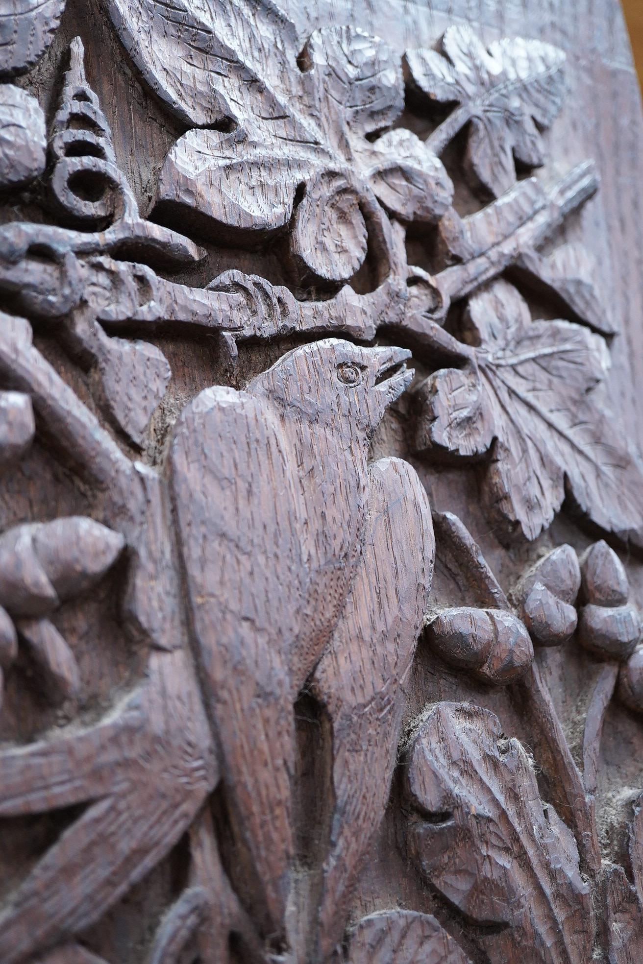 A carved oak relief panel, of acorns, oak leaves and a bird, 64cm high, 33cm deep